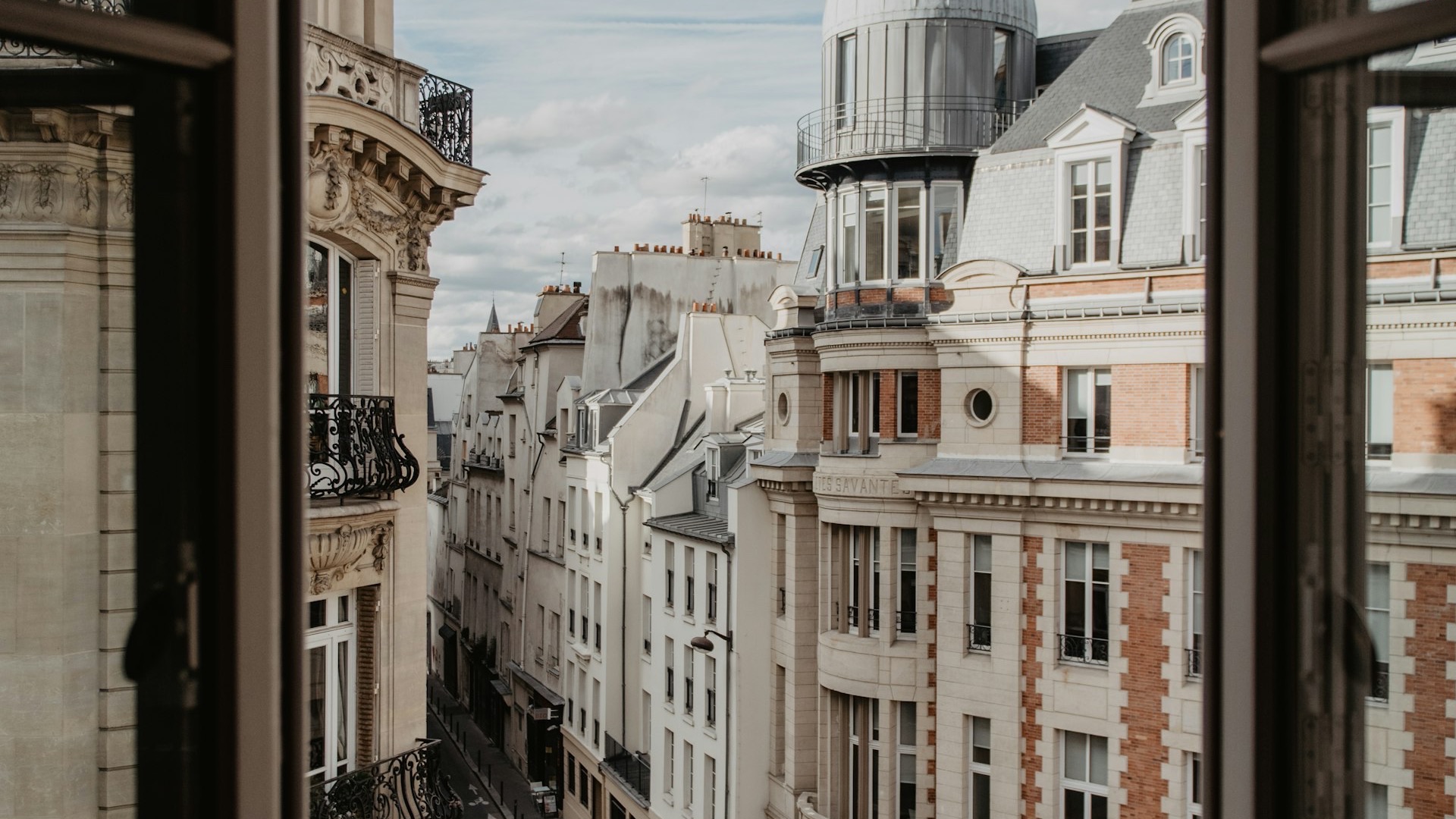 A Paris street of Haussmannian facades seen through an open window, illustrating the French property market as it looks from the outside